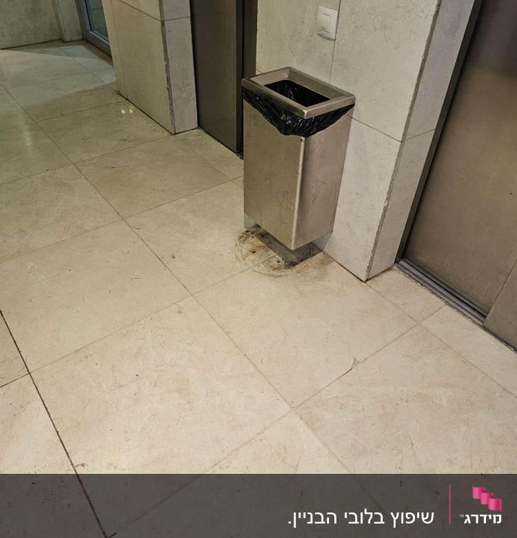 פח אשפה מתכת ליד מעלית על רצפת שיש